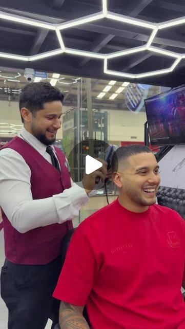 Barbero con chaleco vinotinto atendiendo una barba